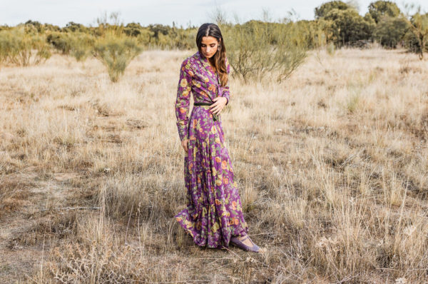 La modelo de Bohemian Shoes posa de pies en el campo a primeros de mayo. Viste un vestido largo de color malva con estampado de flores de La Costa del Algodón, y calza una par de zapatos de mujer tipo Mary Jane T-bar en color malva